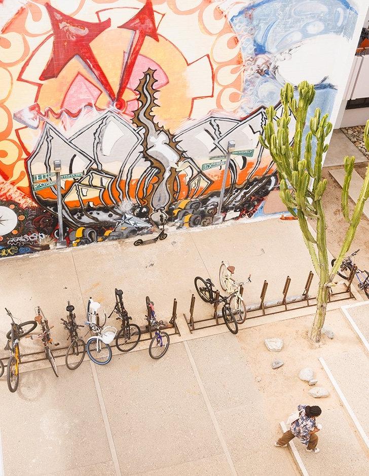 a student walks past parked bikes and a mural in mead courtyard